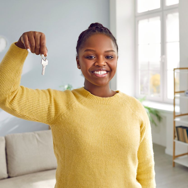 Étudiante souriante tenant les clés de son nouveau logement après un déménagement réussi